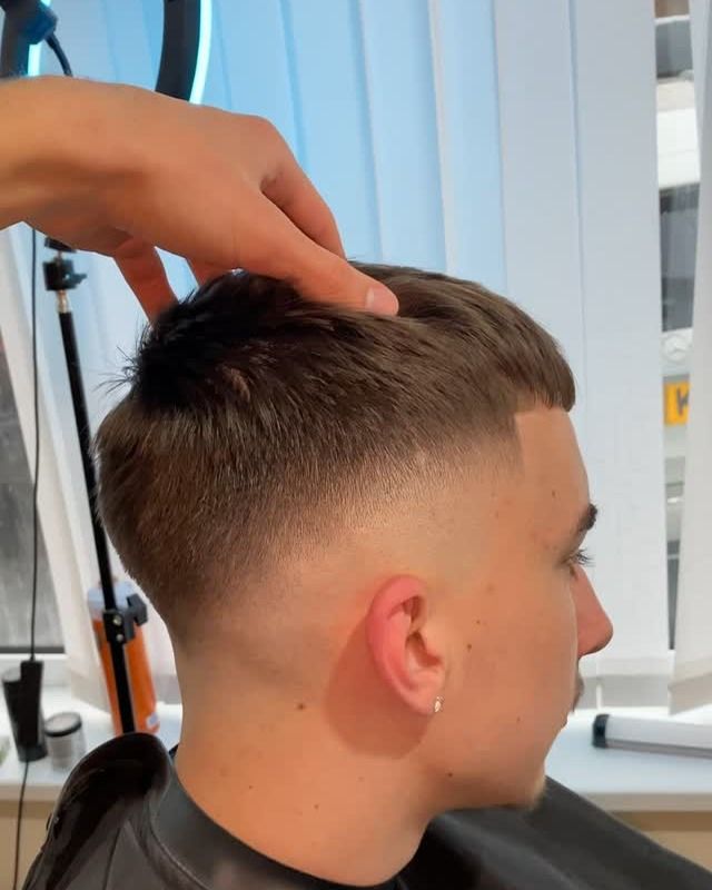 Flavi checking the top of a client's textured cut in the mirror