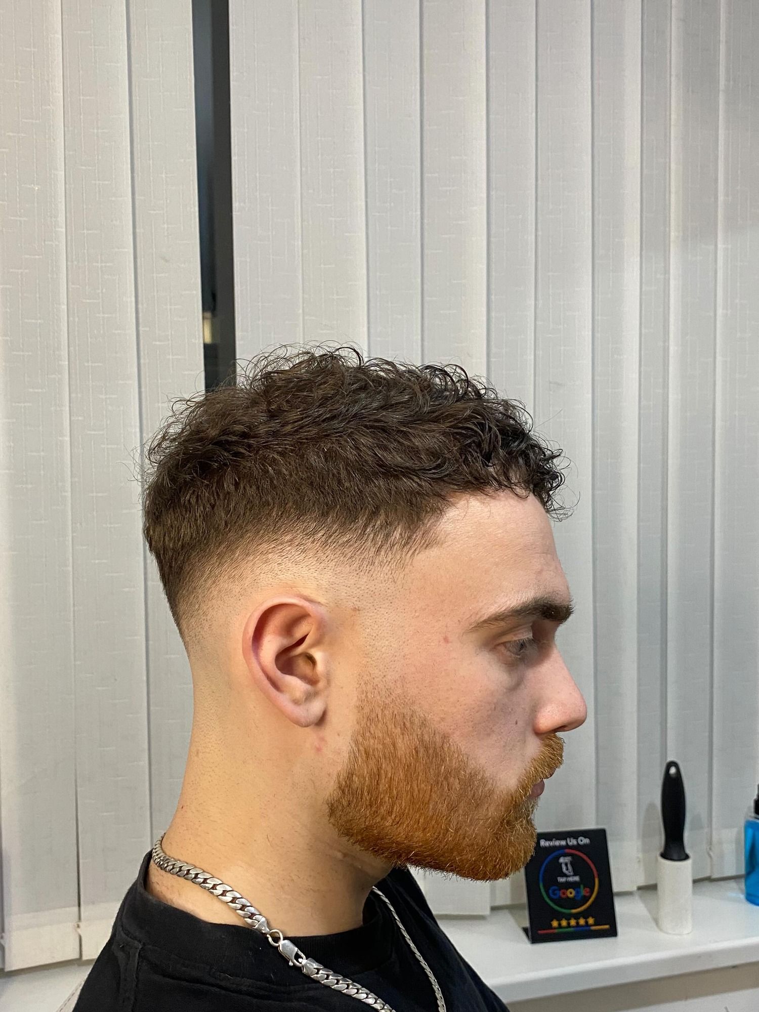 Side profile of a fresh mid fade with the beard lined up, cut by Flavi in Nottingham